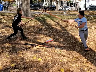 Genevieve-practicing kung fu long staff with fellow trainee